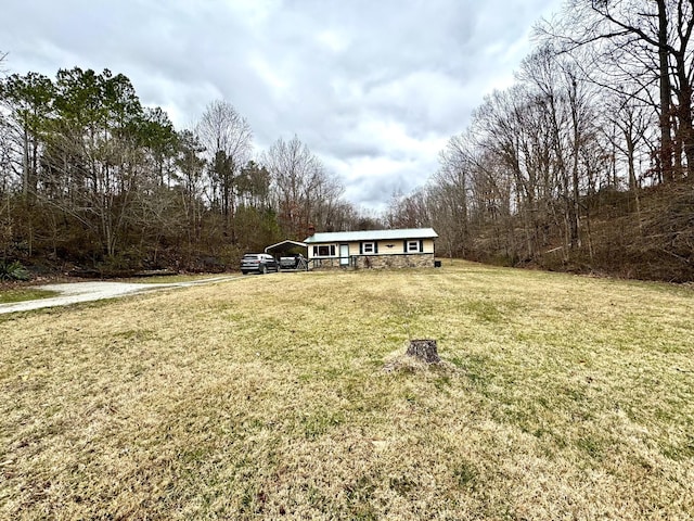 view of front of property featuring stone siding, a carport, and a front yard