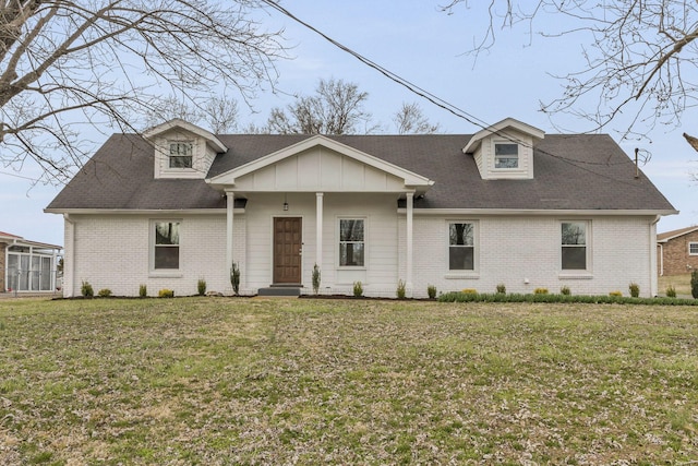 view of front of property with a shingled roof, brick siding, and a front lawn