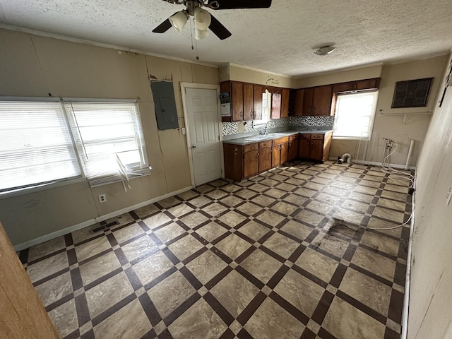 kitchen with a sink, visible vents, baseboards, light countertops, and electric panel