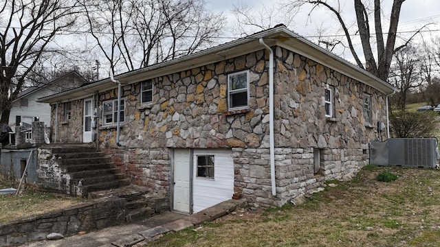 view of property exterior with stone siding and central AC