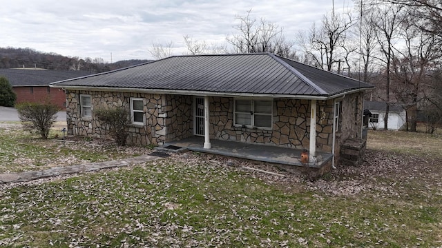 view of front of house with stone siding, a porch, and metal roof