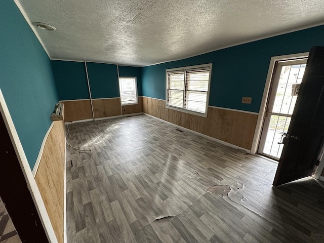 interior space with a wainscoted wall, plenty of natural light, and wood finished floors