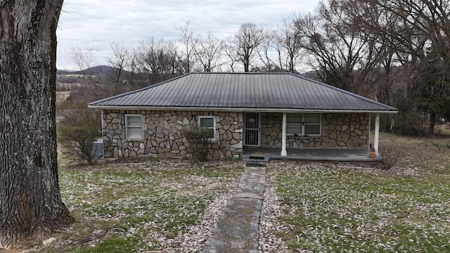 view of front of house with stone siding, covered porch, and metal roof