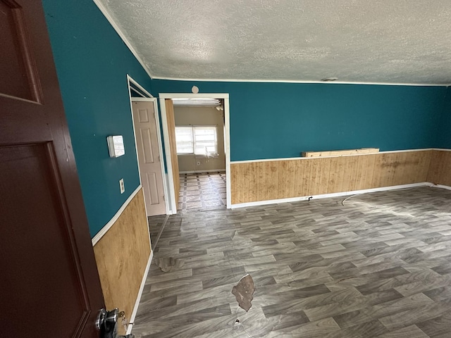 spare room featuring a wainscoted wall, a textured ceiling, and wooden walls