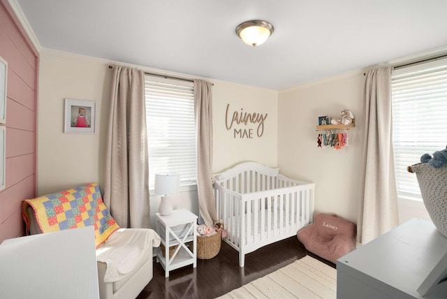 bedroom featuring ornamental molding, a crib, and wood finished floors