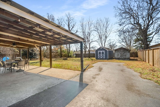 view of patio / terrace with an outbuilding, a fenced backyard, outdoor dining space, and a storage unit