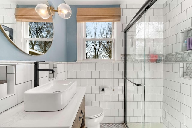 bathroom with a stall shower, tile walls, toilet, and vanity