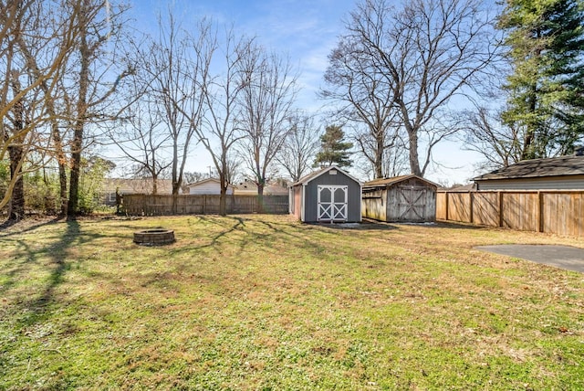 view of yard featuring a shed, a fire pit, a fenced backyard, and an outdoor structure