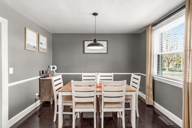 dining room with dark wood finished floors, visible vents, and baseboards