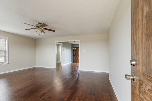 empty room featuring a ceiling fan, dark wood finished floors, and baseboards