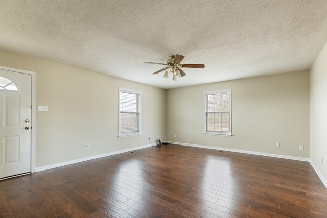 empty room with ceiling fan, a textured ceiling, baseboards, and dark wood-style flooring