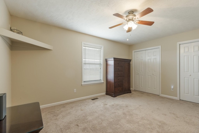 unfurnished bedroom with multiple closets, a textured ceiling, baseboards, and carpet flooring