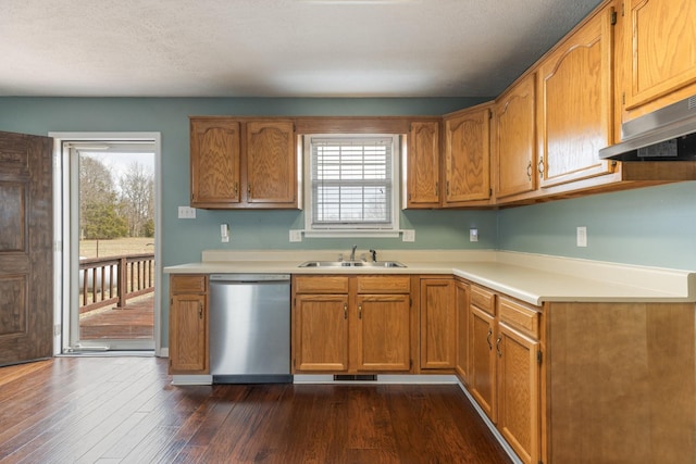 kitchen featuring dark wood finished floors, stainless steel dishwasher, light countertops, under cabinet range hood, and a sink