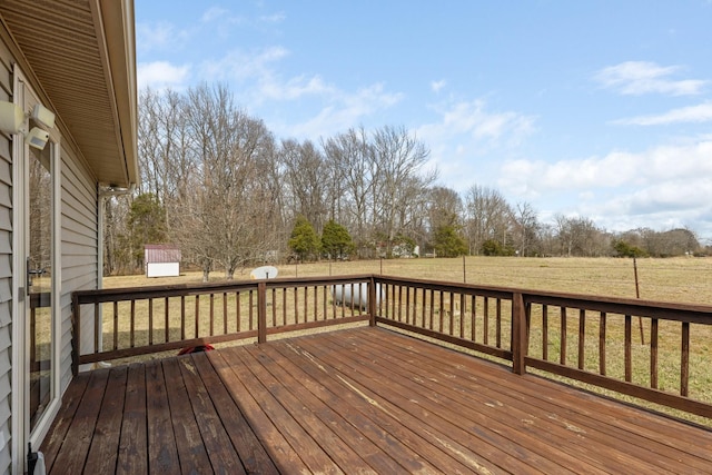 wooden terrace featuring a rural view, a lawn, and fence