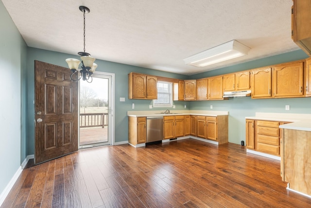 kitchen with dark wood-type flooring, a sink, hanging light fixtures, stainless steel dishwasher, and light countertops