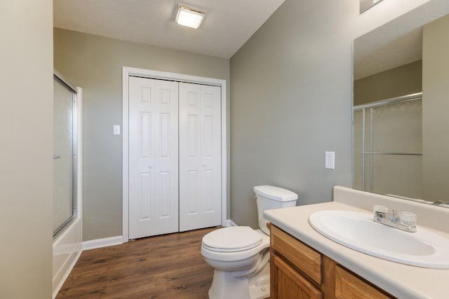 full bath featuring combined bath / shower with glass door, vanity, toilet, and wood finished floors