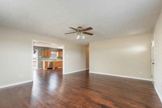 unfurnished living room featuring baseboards, dark wood finished floors, and a ceiling fan