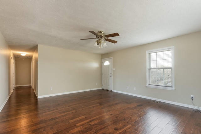 empty room with ceiling fan, dark wood finished floors, attic access, and baseboards