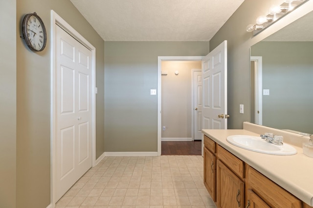 bathroom featuring vanity, baseboards, and a textured ceiling