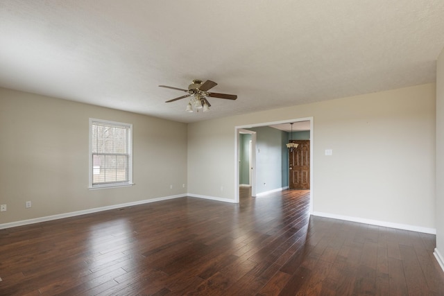 spare room with baseboards, dark wood-type flooring, and ceiling fan with notable chandelier