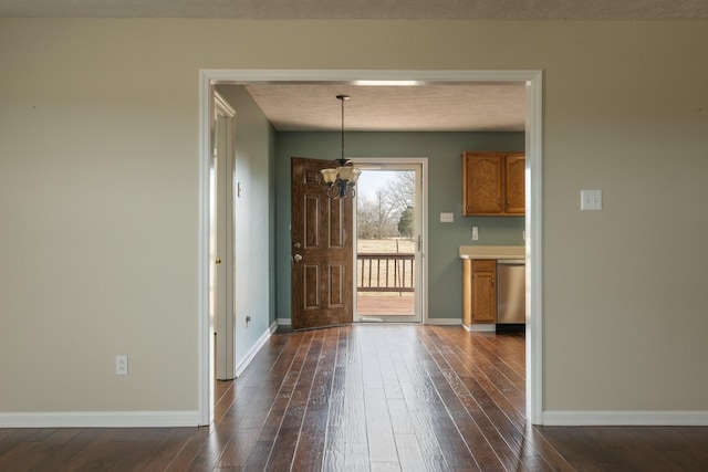 foyer featuring baseboards, dark wood finished floors, a textured ceiling, and a chandelier