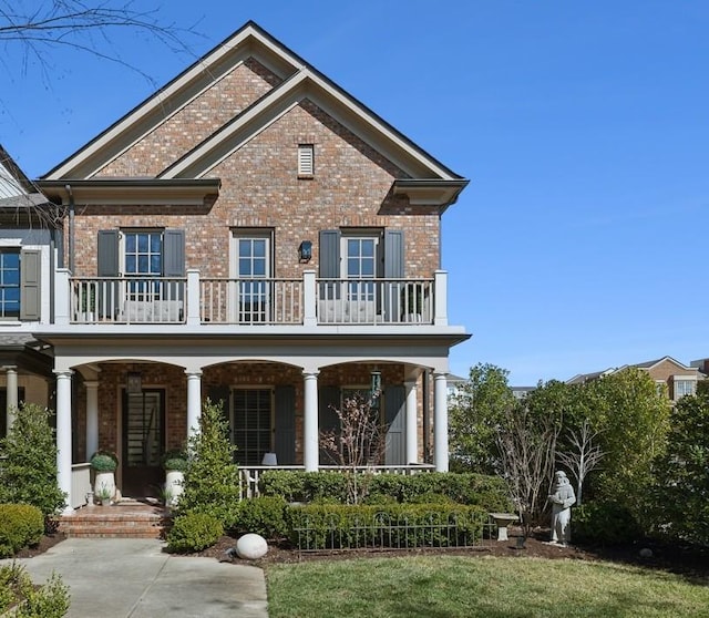 rear view of property with covered porch, brick siding, and a balcony