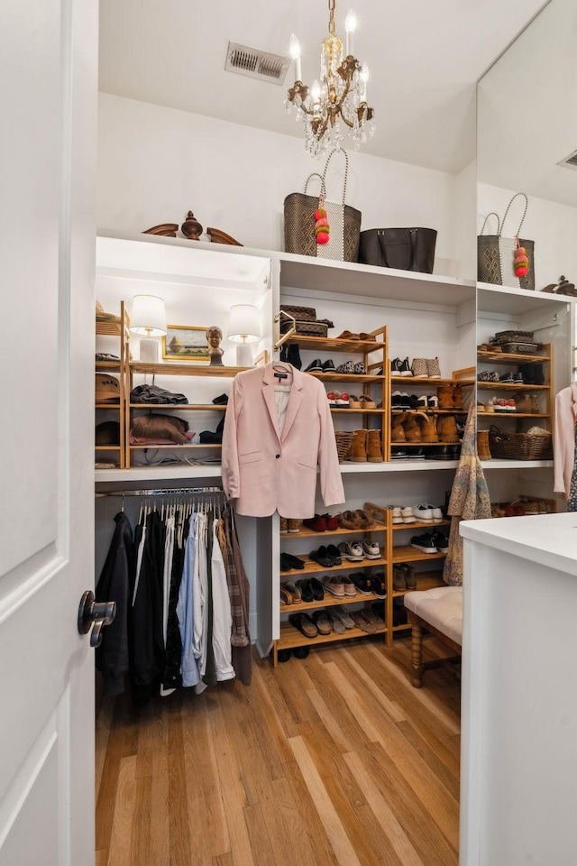 walk in closet featuring a chandelier, wood finished floors, and visible vents