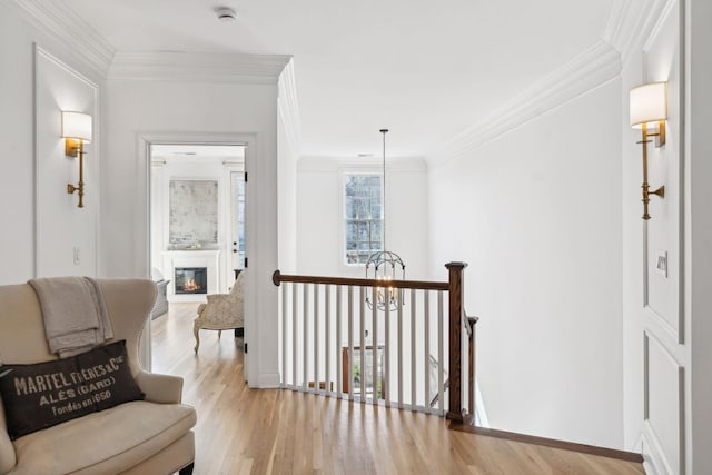 hall with an upstairs landing, crown molding, a notable chandelier, and wood finished floors