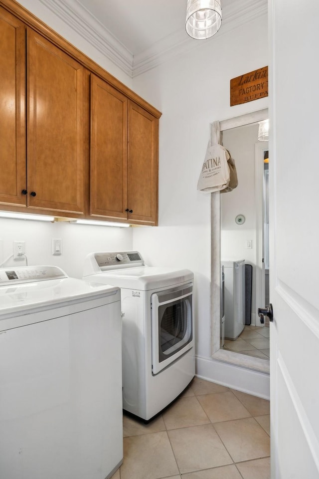 clothes washing area with washer and dryer, cabinet space, crown molding, and light tile patterned flooring