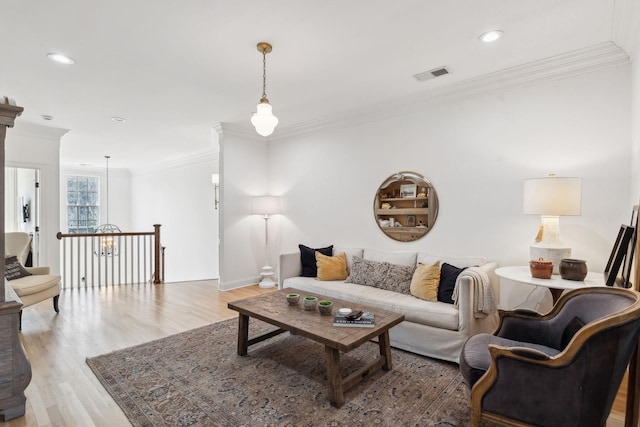 living room featuring light wood-style floors, recessed lighting, visible vents, and ornamental molding