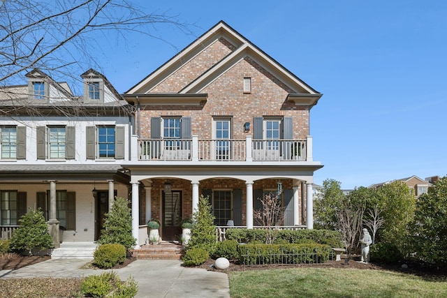 view of front facade featuring covered porch, brick siding, and a balcony