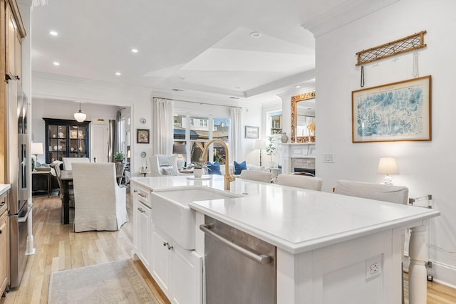 kitchen featuring a fireplace, a sink, light wood-style floors, open floor plan, and appliances with stainless steel finishes