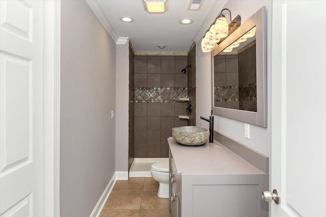 full bathroom with toilet, vanity, baseboards, a tile shower, and crown molding