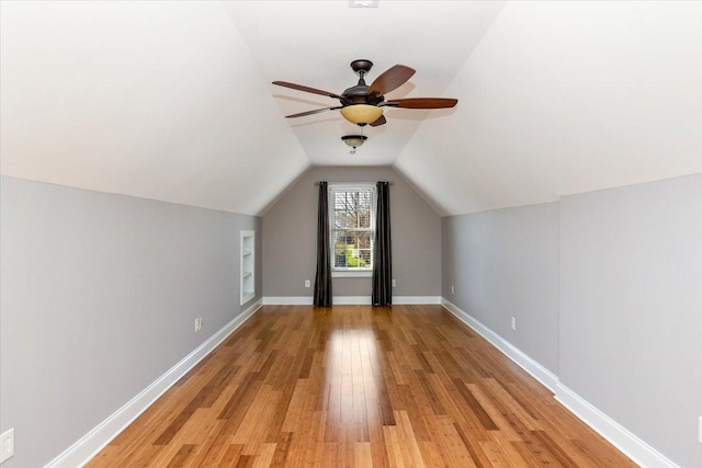 bonus room with a ceiling fan, vaulted ceiling, light wood-style flooring, and baseboards