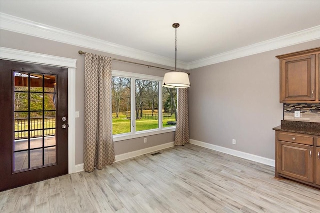 unfurnished dining area featuring visible vents, ornamental molding, light wood-style flooring, and baseboards