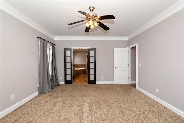 unfurnished room with crown molding, carpet, a ceiling fan, and baseboards