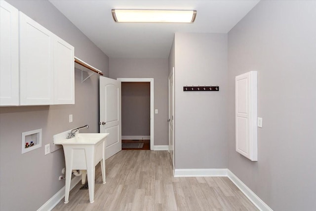 laundry area with light wood-style floors, washer hookup, cabinet space, and baseboards