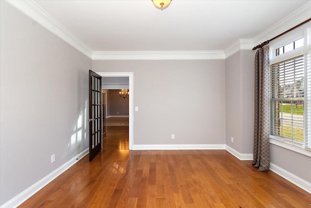 empty room featuring crown molding, baseboards, and wood finished floors