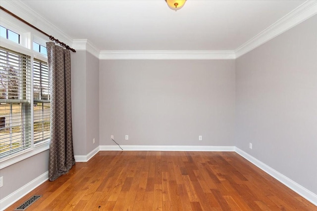 unfurnished room with baseboards, visible vents, wood finished floors, and ornamental molding