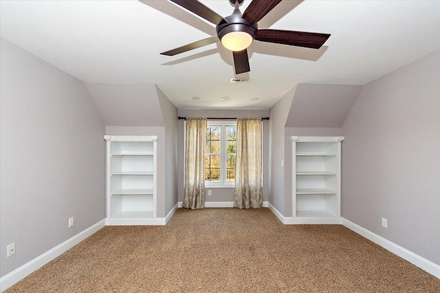 additional living space with visible vents, baseboards, vaulted ceiling, carpet flooring, and built in shelves