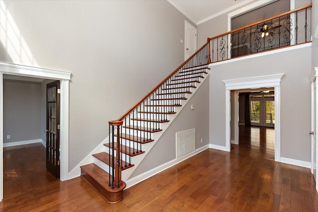 stairway featuring french doors, visible vents, a towering ceiling, and wood finished floors