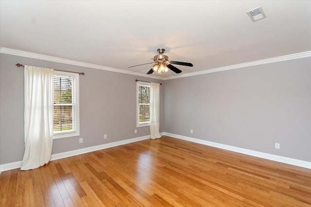 empty room with light wood-style floors, visible vents, crown molding, and baseboards