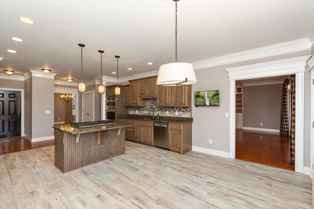 kitchen featuring a breakfast bar, a center island, stainless steel appliances, light wood-style floors, and backsplash