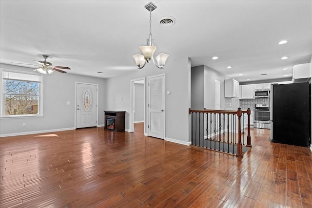 unfurnished living room featuring visible vents, baseboards, and wood finished floors