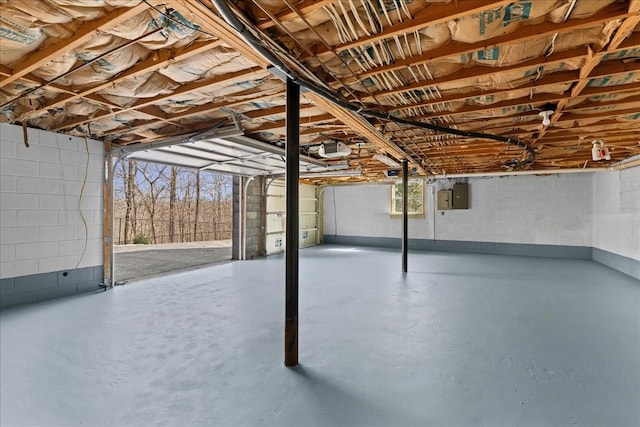 below grade area featuring a garage, electric panel, and concrete block wall