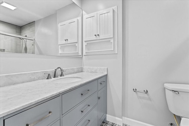 full bathroom featuring toilet, baseboards, tiled shower, and vanity