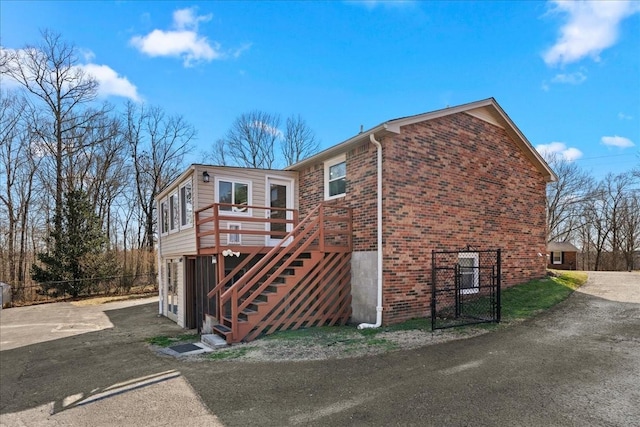 exterior space featuring stairs, brick siding, fence, and a deck