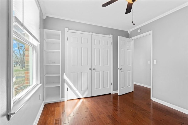 unfurnished bedroom featuring crown molding, a closet, wood finished floors, and baseboards