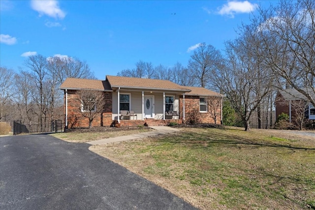 single story home featuring a front yard, a porch, and brick siding