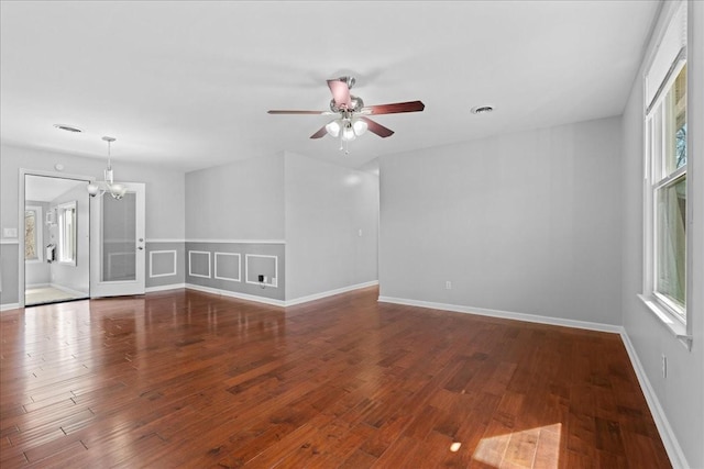 unfurnished room featuring baseboards, wood finished floors, and ceiling fan with notable chandelier